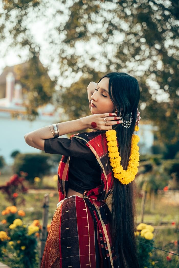 A beautiful young woman poses outdoors in traditional attire, showcasing South Asian aesthetics.